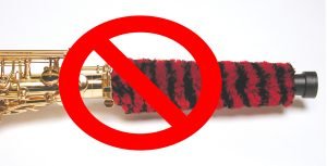 saxophone pad saver, red and black fuzzy pad saver sticking out of the end of an alto saxophone, red circle with a line through it over the image indicating to not use this type of product on a saxophone